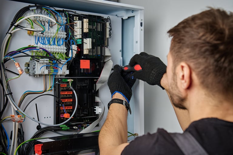 Electrician servicing electrical panel with screwdriver