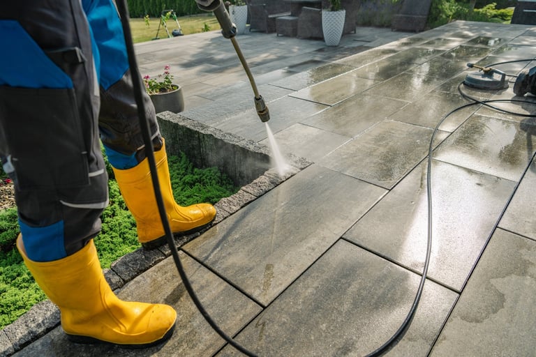 Worker cleaning a stone patio with pressure washer